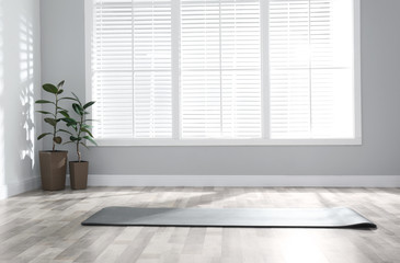 Unrolled grey yoga mat on floor in room