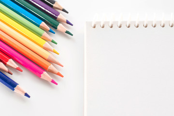 notepad with color pencil on white table view from above