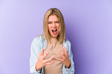 Young blonde caucasian woman isolated screaming with rage.