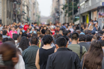 A crowd of crowded people walking side by side as they cross a street