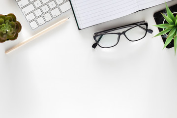 Office desk with white empty space for text. Copy space. Keyboard, open notebook, glasses and plants. Office accessories. Marble pattern.