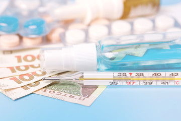 Hryvnia banknotes. Concept of expensive medecine. Reduce the risk of infection. The concept of protection against airborne diseases. Coronovirus and flu. Pills, spray, antiseptic on a blue background