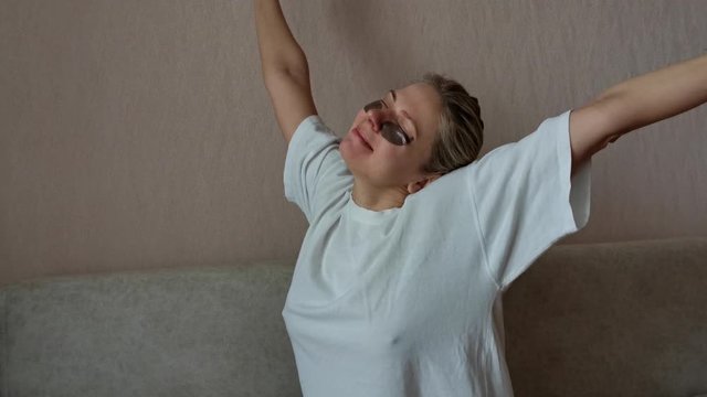 a young beautiful girl with black eye patches. a young woman yawns. morning facial treatments.