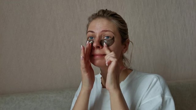 a young beautiful girl with black eye patches. morning facial treatments.