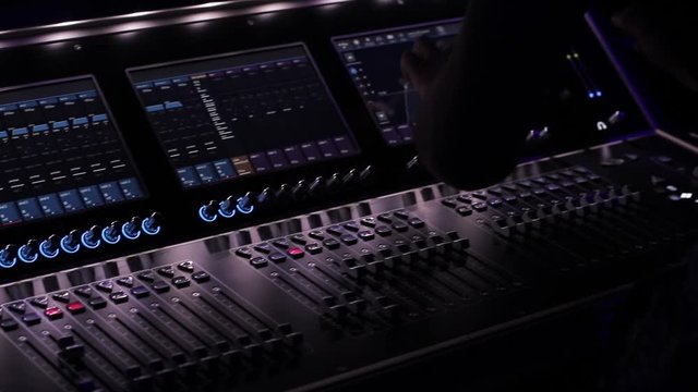 Audio mix desk at a concert. Man working on professional digital audio channel mixer in studio. Male Dj hands playing set in night club party slow motion