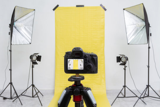 Camera in a photo studio with yellow backdrop and light equipment