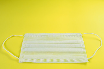 White medical mask on yellow background. Protection against coronavirus, allergies, flu. Surgical mask