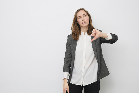 Businesswoman is pointing the thumb down while looking resignedly