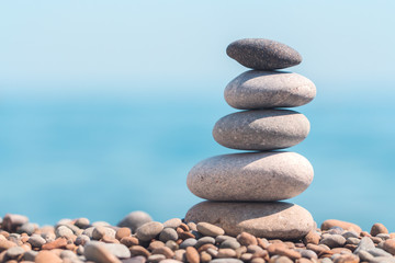 Stack stones on the coast of the sea in the nature. Cairn on the ocean beach, five pebbles tower. Concept of balance and harmony. Calm and spirit