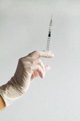 female doctor holds a syringe in his hand isolated on a white background. The doctor in white gloves holds a syringe, ready to give an injection for treatment