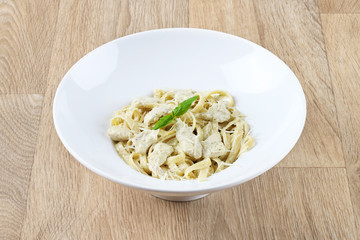 alfredo pasta with basil leaves and Parmesan cheese in a white plate on a wooden background