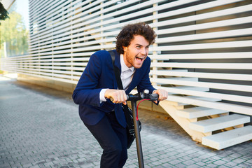 Young man in a helmet rides an electric scooter on a city street in summer © Studio Romantic