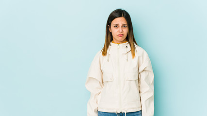 Obraz premium Young woman isolated on blue background blows cheeks, has tired expression. Facial expression concept.
