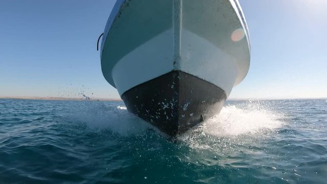 Splashing water and crashing waves at bow of a fishing boat sailing over the Red Sea towards Umluj, a tropical island group and travel destination in Saudi Arabia