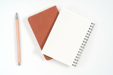 top view blank orange leather diary and pencil on white desk
