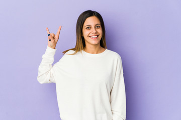 Young woman isolated on purple background showing a horns gesture as a revolution concept.