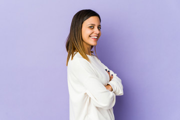 Young woman isolated on purple background who feels confident, crossing arms with determination.