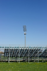 Empty bleachers outside on a soccer field, blue sky and green grass