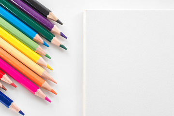 Obraz premium notepad with color pencil on white table view from above