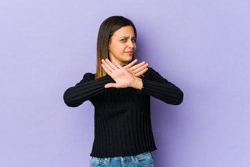 Young woman isolated on purple background doing a denial gesture