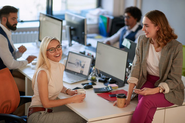 Obraz premium Koledzy kobiety piją kawę w biurze i miło spędzają czas.