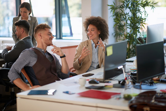 Man And Woman Sitting At Workplace Together, Multi Ethnic Business People At Table  In Office.