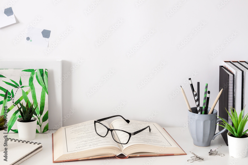 Wall mural school desk on a white wall. school supplies, mug with pencils, books and notebooks, plants and stic