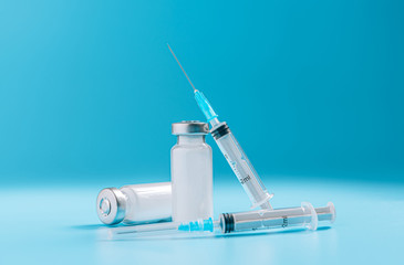 two syringes and two ampoules with medicine without a label on a blue background the concept of a...