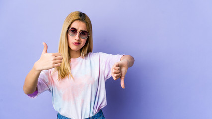 Young hipie woman with glasses isolated on purple background showing thumbs up and thumbs down,...