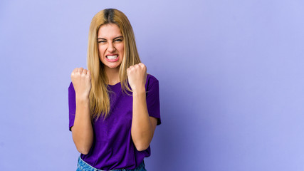 Plakat Young blonde woman isolated on purple background showing fist to camera, aggressive facial expression.