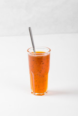 Herbal berry drink sea buckthorn with oregano in a glass on a white background
