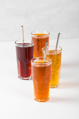 Herbal fruit berry cocktail in a glass, pineapple with Basil, pomegranate with mint, sea buckthorn with oregano on a light background