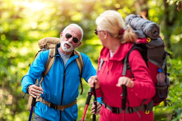 Happy senior couple of hikers  in the forest.