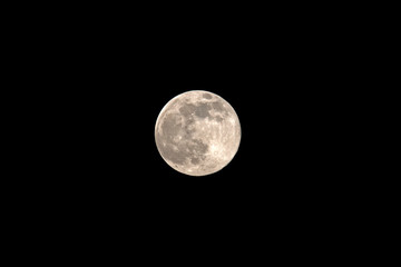 Full moon with a yellowish tinge on the dark background of the sky