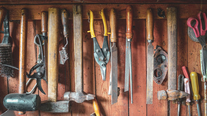 Vintage tools hanging on the wall of old rustic shed