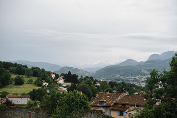 European rural country side highland village view. Photography of houses on the edge of mountain forest and clody sky.