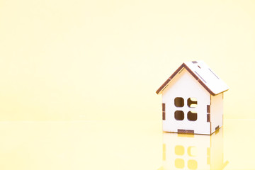 small wooden decorative on a yellow background, reflection in the glass, copy space, purchase, sale and rental of real estate concept, building a house