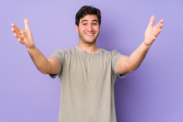 Fototapeta premium Young man isolated on purple background celebrating a victory or success, he is surprised and shocked.