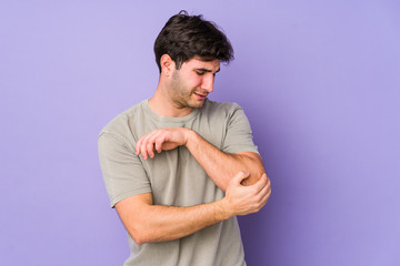 Young man isolated on purple background massaging elbow, suffering after a bad movement.