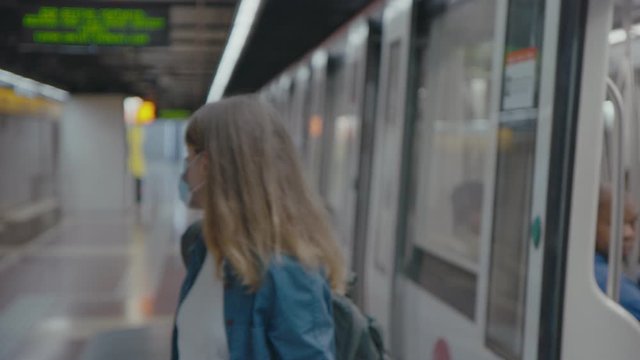 Soft focus blurred motion shot of young worried female quickly leave metro carriage on empty station. Woman in medical face mask runs out of metro stop during coronavirus outbreak