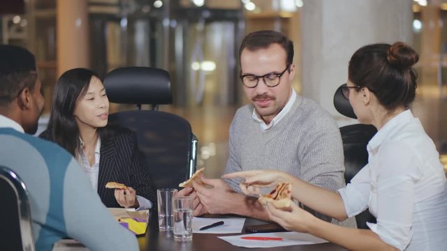 Happy young diverse business team eating pizza in office