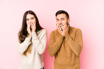 Young caucasian couple isolated laughing about something, covering mouth with hands.