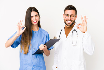 Young doctor man and a nurse isolated cheerful and confident showing ok gesture.