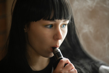 Vaping teenager. Young pretty white caucasian teenage brunette girl with blue eyes and problem skin...