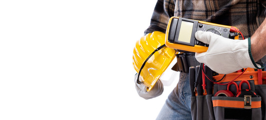 Electrician holds multimeter tester in hand, helmet with protective goggles. Construction industry,...