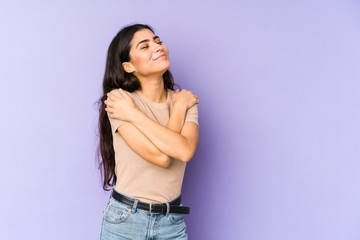 Young indian woman isolated on purple background hugs, smiling carefree and happy.