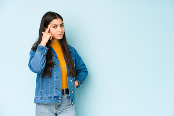 Young indian woman isolated on blue background pointing temple with finger, thinking, focused on a task.