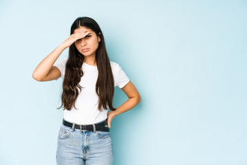 Fototapeta premium Young indian woman on blue background touching temples and having headache.