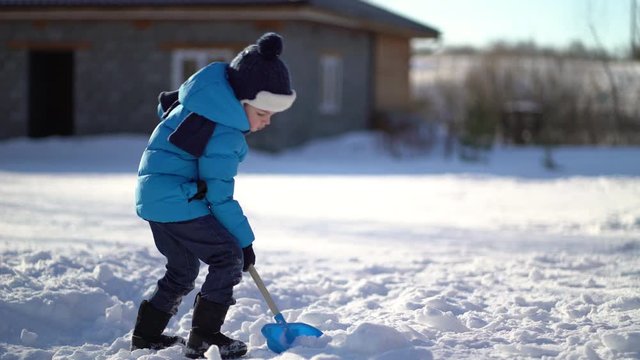 Little boy shoveling snow at winter
