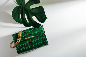 Fashion green handbag with tropical leaf. on white background. Flat lay, top view. Summer fashion concept